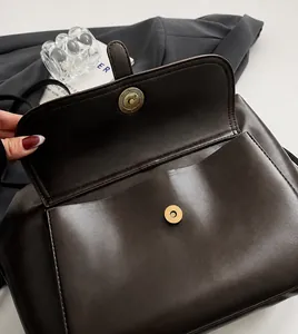 Dettaglio della fibbia magnetica in bronzo e cuciture sulla borsa in pelle marrone