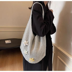 Detail der silbernen Stricktasche mit bunten Pailletten-Sternen auf dem Strickgewebe