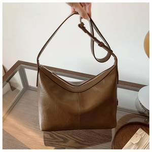 Detailed close-up of dark brown vintage leather shoulder bag with fine stitching