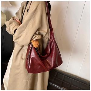 Close-up of deep red leather hobo bag with vintage texture and cute plush bear charm