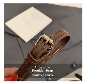 Detail van verstelbare donkerbruine schouderriem van wasleer met zilveren gesp