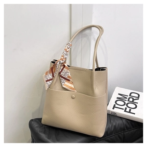 Close-up of beige pebble leather tote bag featuring a decorative patterned silk scarf
