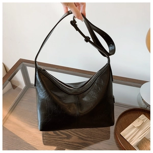 Detail of black glossy hobo bag featuring pleated leather texture and metal zipper