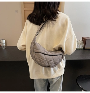 Detailed view of grey quilted crescent bag with adjustable strap on a casual outfit