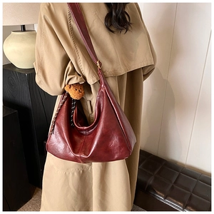 Detail of dark red vintage hobo bag with plush bear charm on soft leather texture