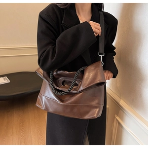 Detail of soft brown PU leather tote bag with thick black twisted handle and wide strap