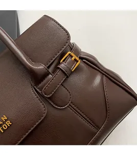Detailed view of hand-stitched leather edge and adjustable gold buckle on a brown tote