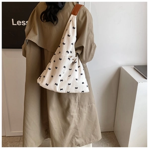 Detail of white canvas tote bag with black bow print and brown leather strap patch