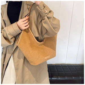 Große braune Hobo-Tasche mit heller Paspelierung getragen zum beigen Trenchcoat