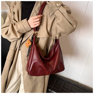 Close-up of a burgundy hobo bag in soft leather with a cute bear plush keychain detail
