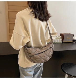 Detail view of large quilted crossbody bag in dark grey nylon with a textured crescent shape
