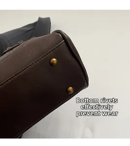 Detail view of brown leather bag bottom with golden protective rivets for anti-wear