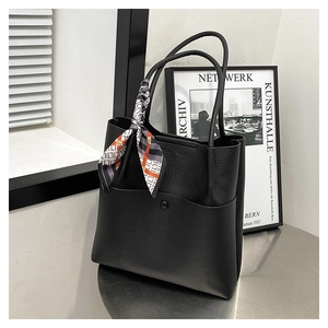 Close-up of black litchi grain leather bucket bag with a stylish geometric print silk scarf