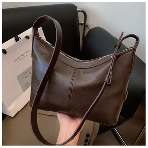 Close-up of dark brown hobo bag with pleated leather texture and dual shoulder straps