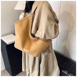 Detailaufnahme der braunen Canvas-Tasche mit Lederriemen und Markenlogo-Aufnäher