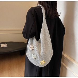 Detailansicht der Strickstruktur der grauen Tasche mit bunten Sternaufnähern und Schleifen