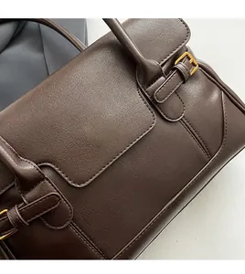 Close-up of dark brown leather texture and golden metal buckle on the shoulder bag