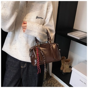 Détail d'un sac Boston marron brillant avec pendentif en corde tressée décorative