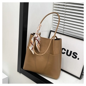 Brown bucket bag with pebble leather texture and a stylish printed silk scarf detail