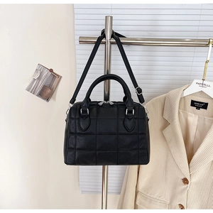 Close-up of black quilted leather Boston bag with round handles and adjustable strap