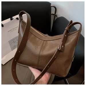 Detail of a brown pleated hobo shoulder bag featuring a silver metal zipper closure
