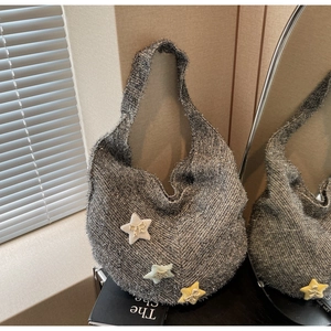 Detail der grauen glitzernden Strick-Hobo-Tasche mit Sternenanhängern im Fensterlicht