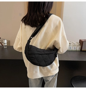 Detail of black quilted puffer bag showing textured nylon fabric and adjustable strap