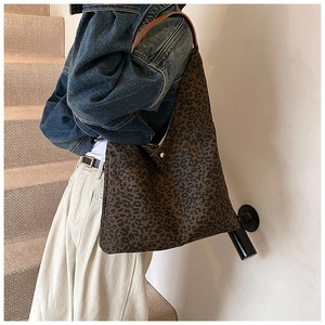 Detail of leopard print tote bag featuring metallic magnetic closure and leather strap