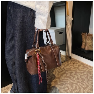 Détail d'un sac Boston marron foncé brillant avec pendentifs en corde tressée