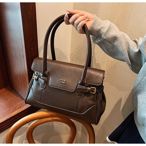 Detailed close-up of dark brown faux leather tote bag with PAN TOR logo on wooden chair