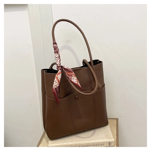 Detailed macro view of brown lychee texture leather tote bag with elegant silk scarf