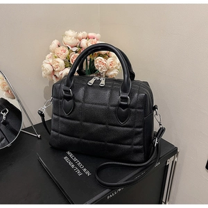 Close-up of black quilted Boston bag with litchi texture and metallic dual zippers