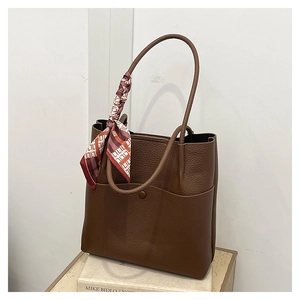 Detail of dark brown lychee leather bucket bag with geometric silk scarf handle decoration