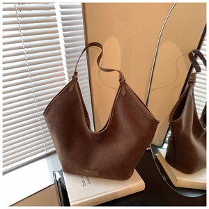 Detailansicht der dunkelbraunen Cord-Hobo-Tasche auf einem Buch in warmer Umgebung