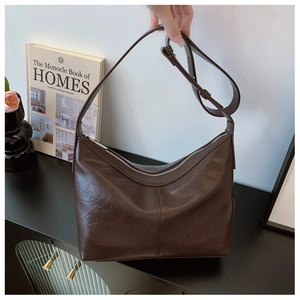 Detail of dark brown faux leather hobo bag with adjustable strap and silver zipper closure