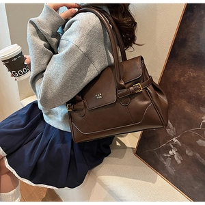 Detail of dark brown leather tote bag with gold buckle and embossed brand logo