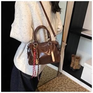 Close-up of deep brown glossy PU leather handbag with detachable strap and woven tassel