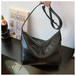 Detail of black hobo bag with glossy crinkled leather texture and silver zipper