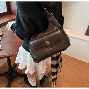 Dettaglio borsa vintage in pelle marrone con tasca anteriore e bottone metallico