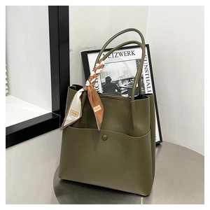 Close-up of olive green tote bag featuring lychee grain leather and silk scarf handle