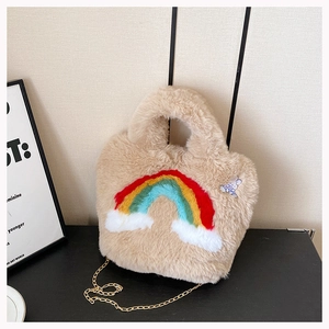 Detail of plush beige handbag with rainbow pattern, rabbit charm and gold chain strap