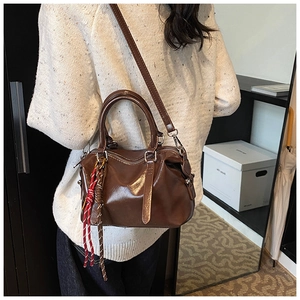 Gros plan sac à main en cuir marron avec charme tressé sur pull en maille