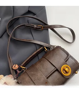 Détail d'un sac bandoulière marron vintage avec fermoir doré et pompon en peluche doux