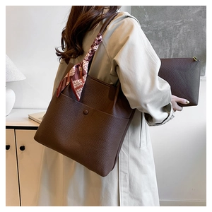 Detail of dark brown lychee textured leather tote bag with a patterned silk scarf handle