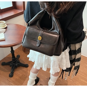 Dettaglio borsa hobo in pelle marrone scuro vintage con fibbia dorata e logo tondo