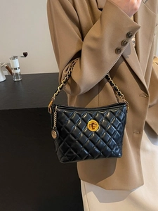 Schwarze gesteppte Schultertasche mit goldener Kette, am Model im schicken Look gezeigt