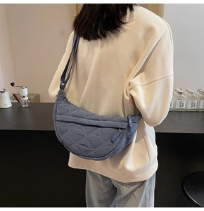 Close-up of a blue-grey quilted crescent bag with diamond stitching and shoulder strap