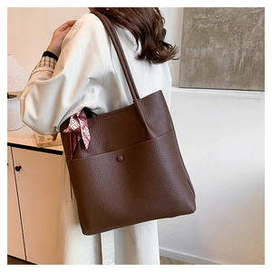 Detail of dark brown leather bucket bag featuring lychee texture and magnetic front pocket