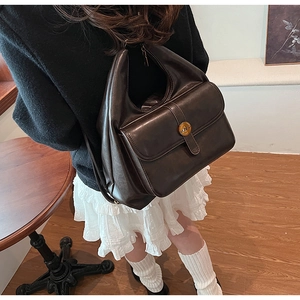 Dettaglio della borsa hobo vintage in pelle caffè scuro con fibbia in metallo dorato e lettera N