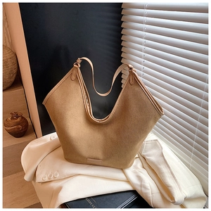 Nahaufnahme der khakifarbenen Canvas-Tasche mit Leder-Logo-Patch auf weißem Anzug